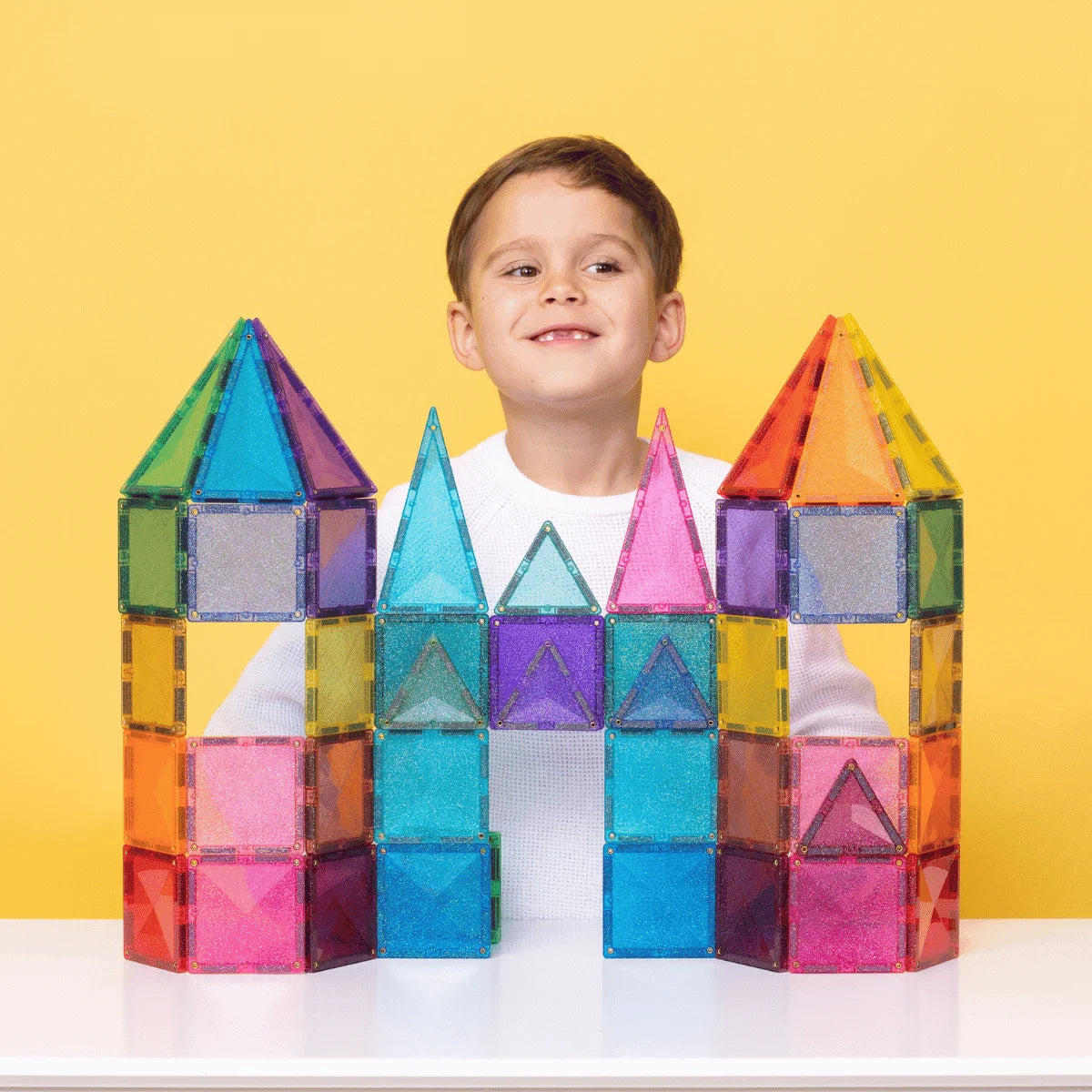 Junger Junge hinter einer bunten Magnetbausteine Glitter Castle Pack 48 stk