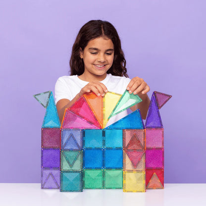 Lächelndes Mädchen spielt mit bunten, durchsichtigen Magnetbausteinen aus dem Glitter Castle Pack