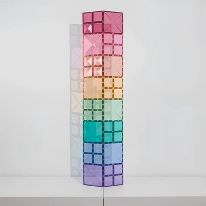 Ein hoher turm aus 40 pastellfarbenen magnetbausteinen in regenbogenfarben von rosa bis lila aus durchsichtigem material