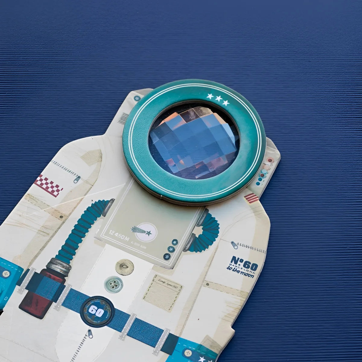 Teal-gerahmte Lupe mit reflektierender Linse auf Major Tom Bee Eye Astronautenanzug aus Patchworkpapier