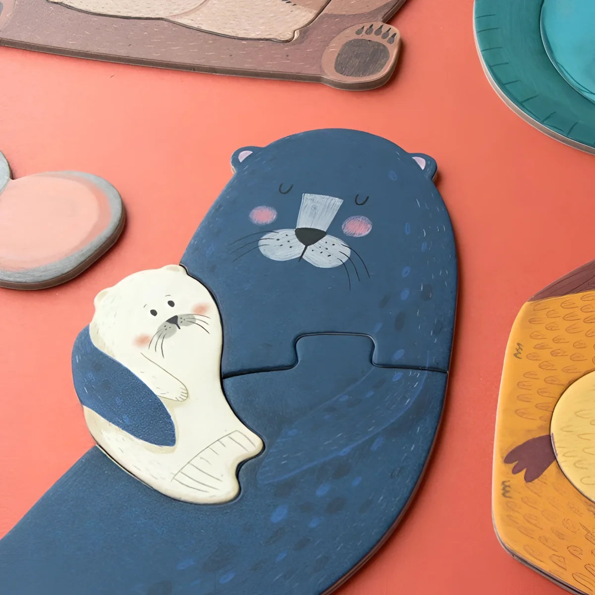 Blauer Cartoonotter hält einen weißen Fisch in dem Produkt Mama Puzzle
