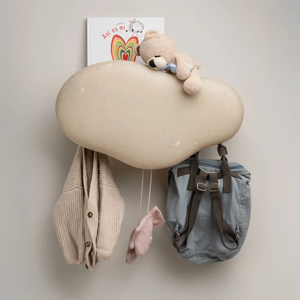 Beiger marine coat rack aus strukturiertem material in wolkenform mit hängenden fächern für jacken und rucksack