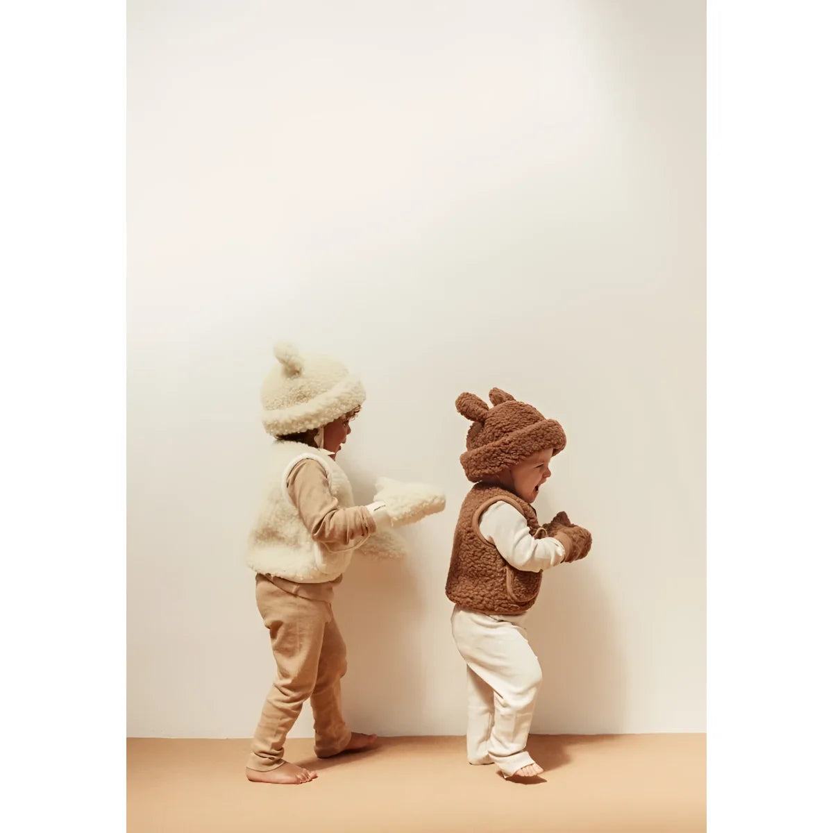 Zwei Kleinkinder in flauschigen tierförmigen Outfits und Hüten, die sich gegenüberstehen