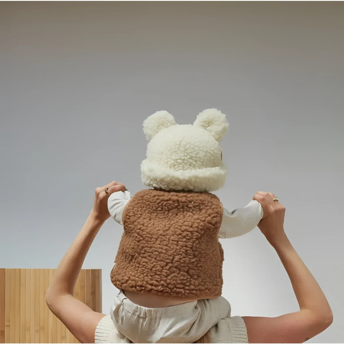 Flauschiger Teddybär mit weißem Hut und braunem Körper in menschlichen Händen