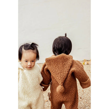 Zwei junge Kinder in flauschigen Onesie-Outfits des Merino Snugglesuit Bruno