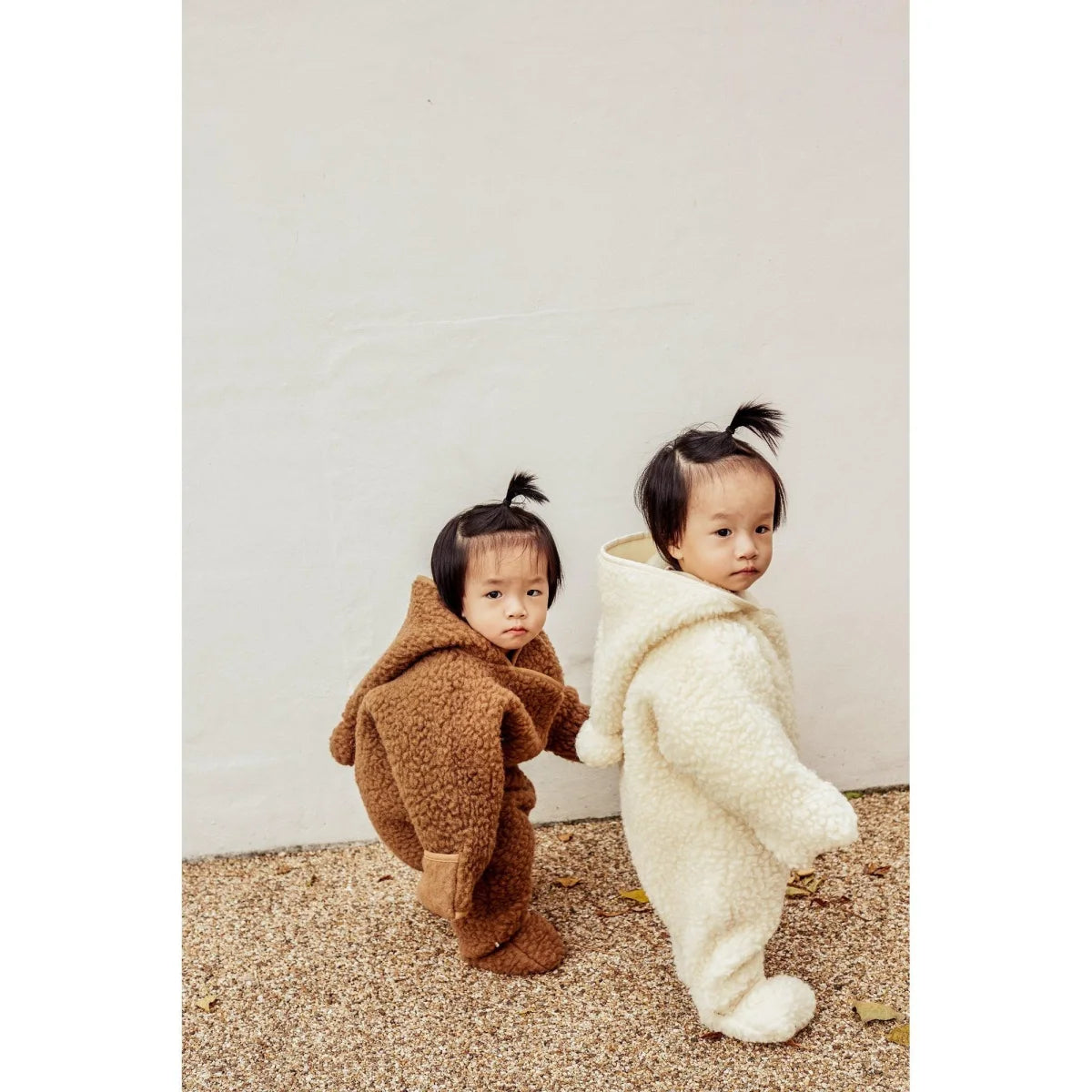 Zwei Kinder in flauschigen Kapuzenanzügen, Merino Snugglesuit in Milchfarbe