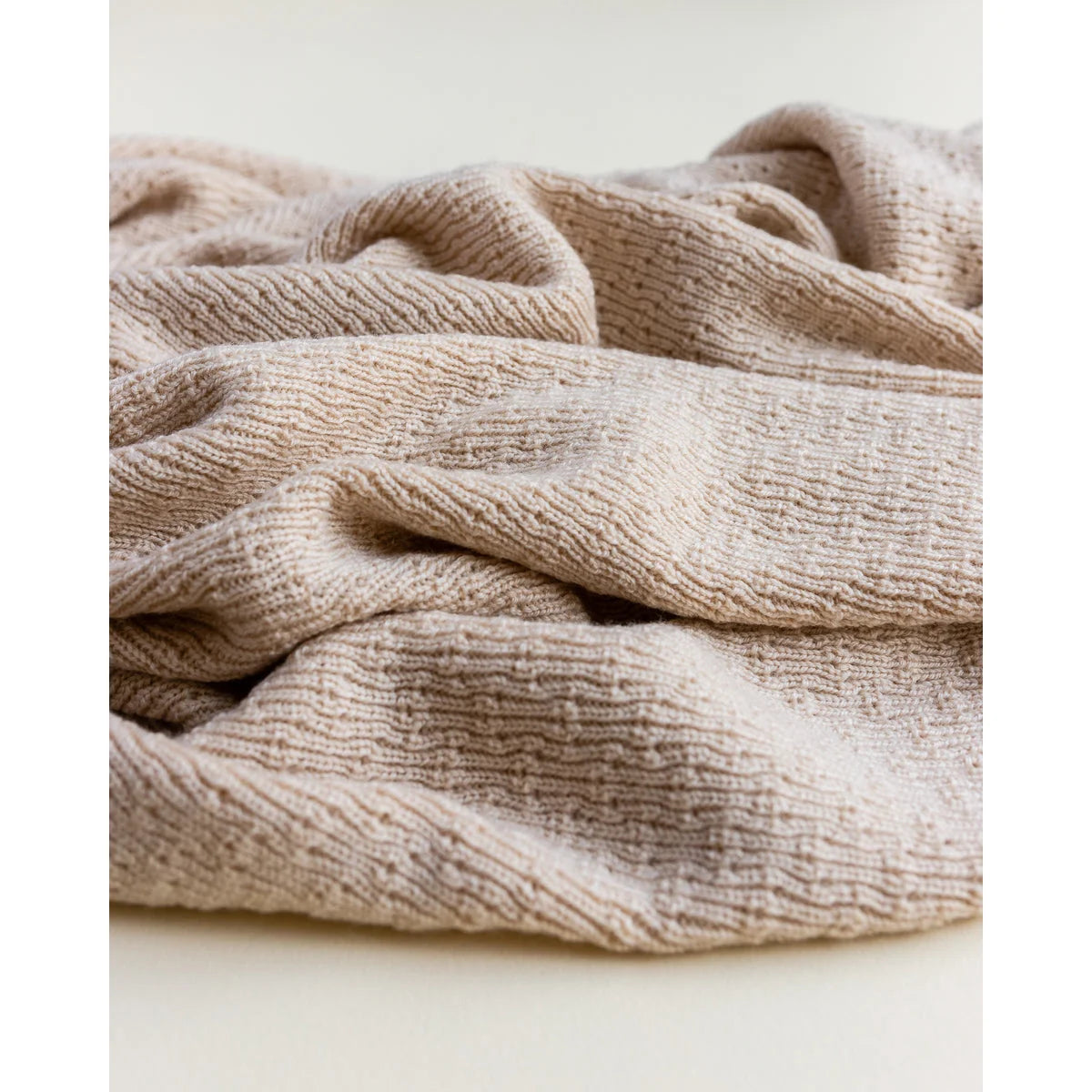 Weiche, strukturierte beige Stoffdecke mit sanften Falten in der Merino Strickdecke Dora