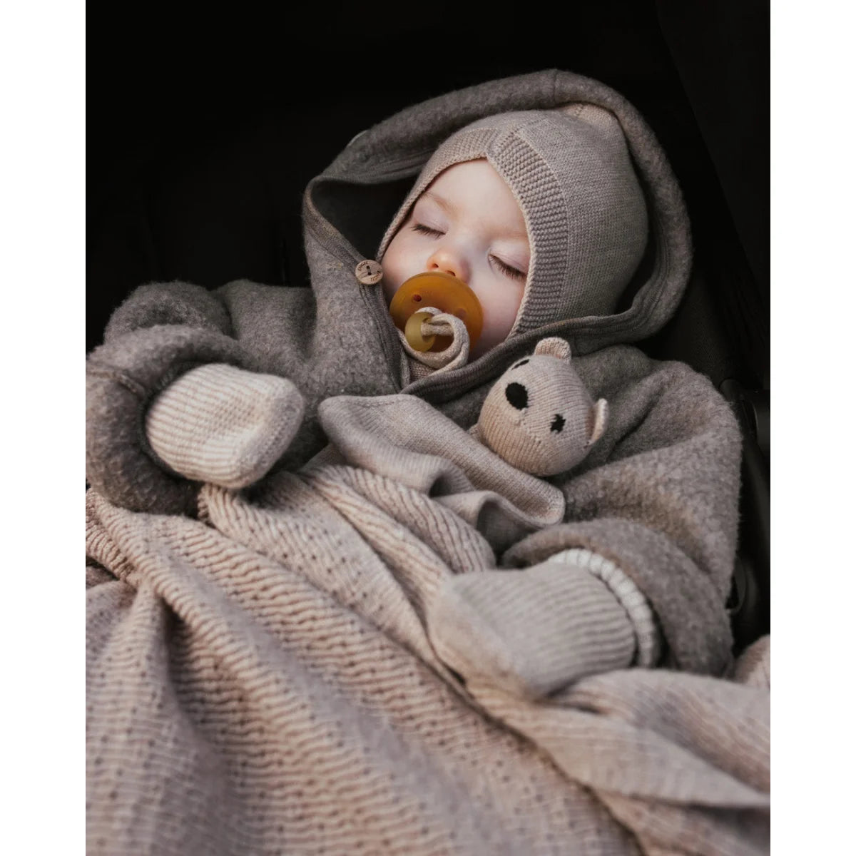 Baby in weicher grauer Strickkleidung mit Schnuller und Decke Merino Strickdecke Dora
