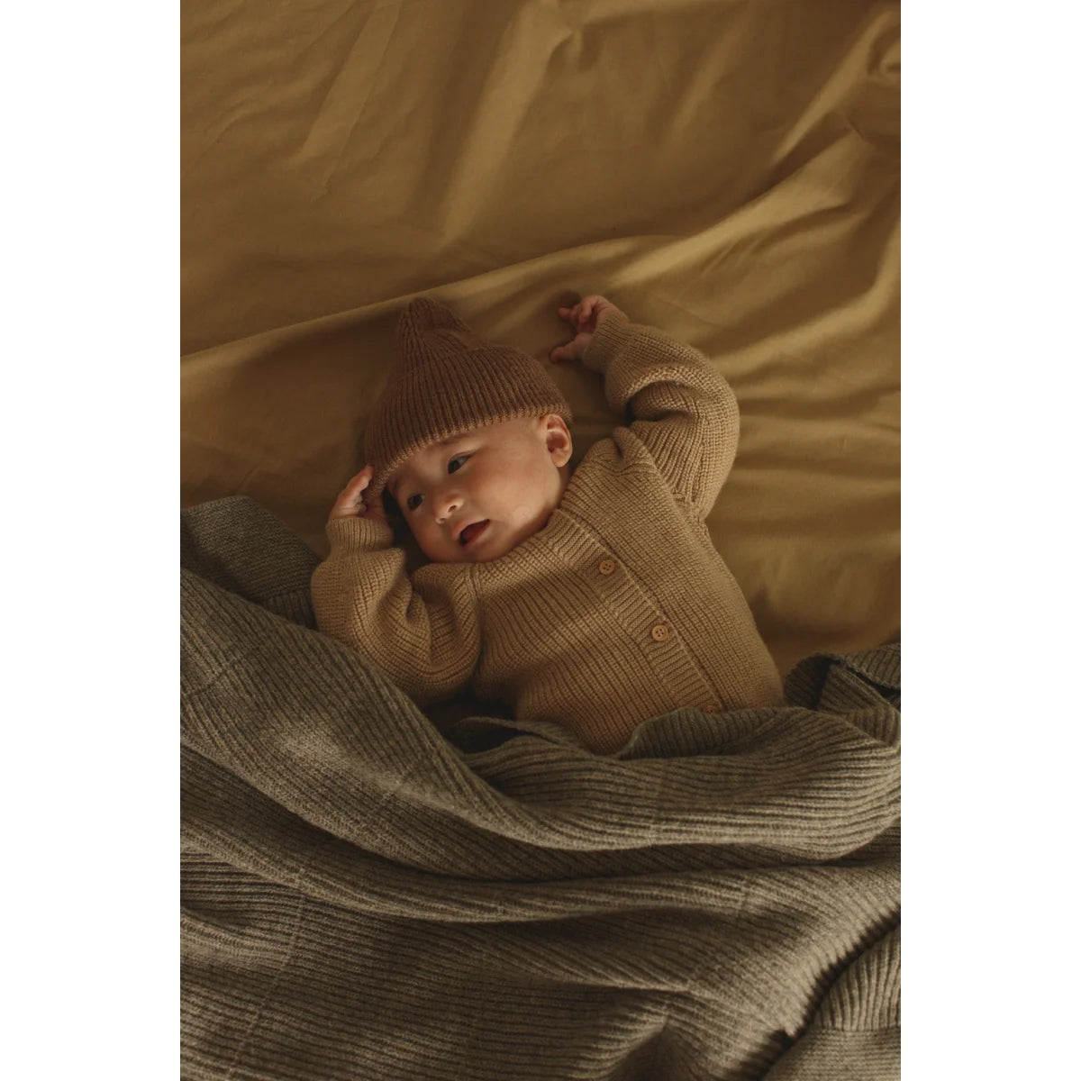 Baby schläft in einer gemütlichen Strickdecke Gaston aus Merinowolle