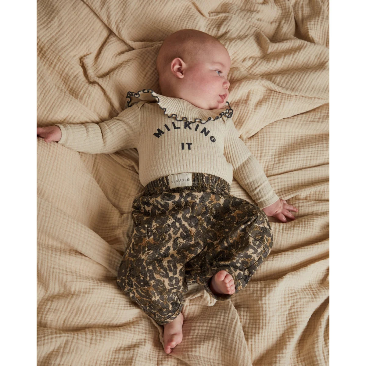 Creamfarbener gerippter strick langarm bodysuit mit schwarzem milking it schriftzug und gerafftem kragen zu oliv-beigem