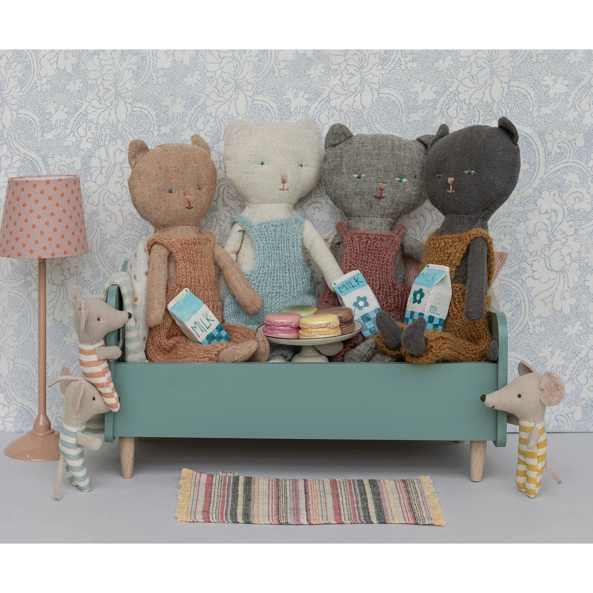 Gruppe von Plüschspielzeugen auf einer kleinen Couch mit Miniatur Stehleuchte