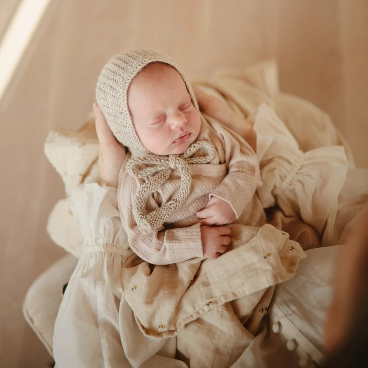 Schlafendes Baby in Mütze mit Mulltuch Bees auf einem weißen Hintergrund