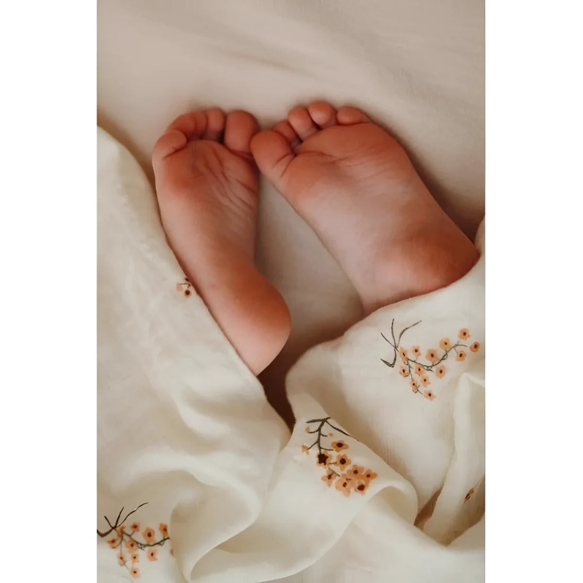 Babys Füße ruhen auf gesticktem Stoff des Produkts Mulltuch Flower