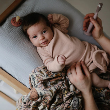 Baby in pale pink outfit on floral blanket from Mulltuch Retro Flowers