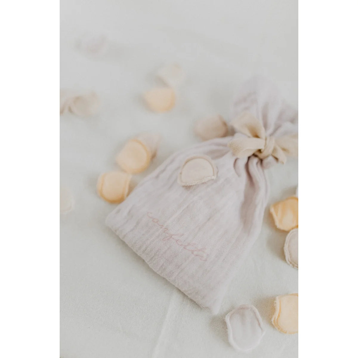 Ein zarter offwhite muslin konfetti beutel mit rosa stickerei und gerafftem top für ökologische baby- und kinderprodukte