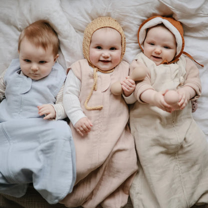 Drei Babys in gemütlichen Schlafanzügen und Mützen im Musselin Schlafsack Fog