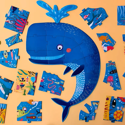 Fröhlicher blauer Cartoonwal umgeben von Puzzlestücken in My Big Blue Puzzle