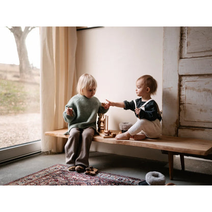 Zwei kleinkinder auf einer bank spielen mit natürlichem stapelspielzeug aus ökologischen baby- & kinderprodukten
