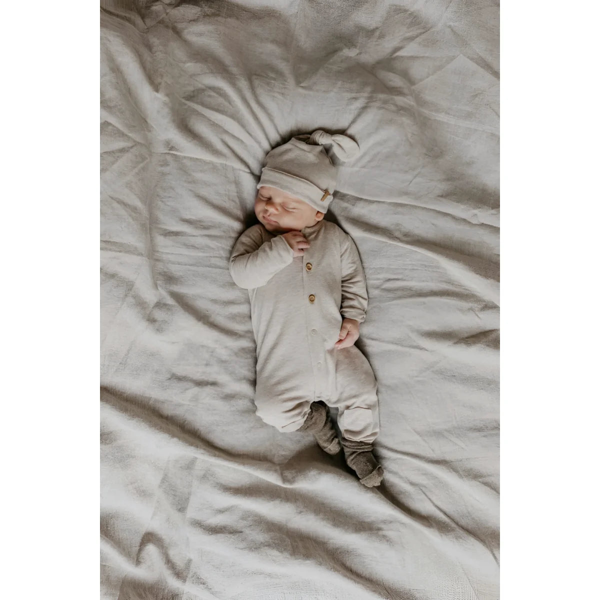 Schlafendes Baby in beiger Kleidung mit Newbie Hut in Beige