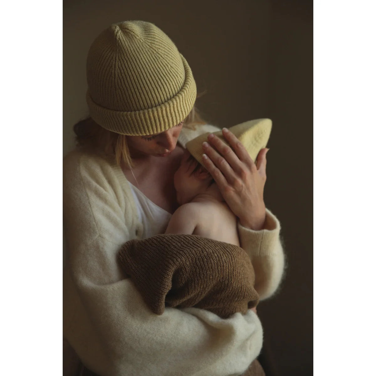Person mit gelber Strickmütze hält Baby im Newborn Beanie Fonzie in Hellgelb