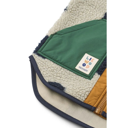 Cozy noam pile vest in cream shearling with forest green nylon and mustard yellow patches with navy blue trim