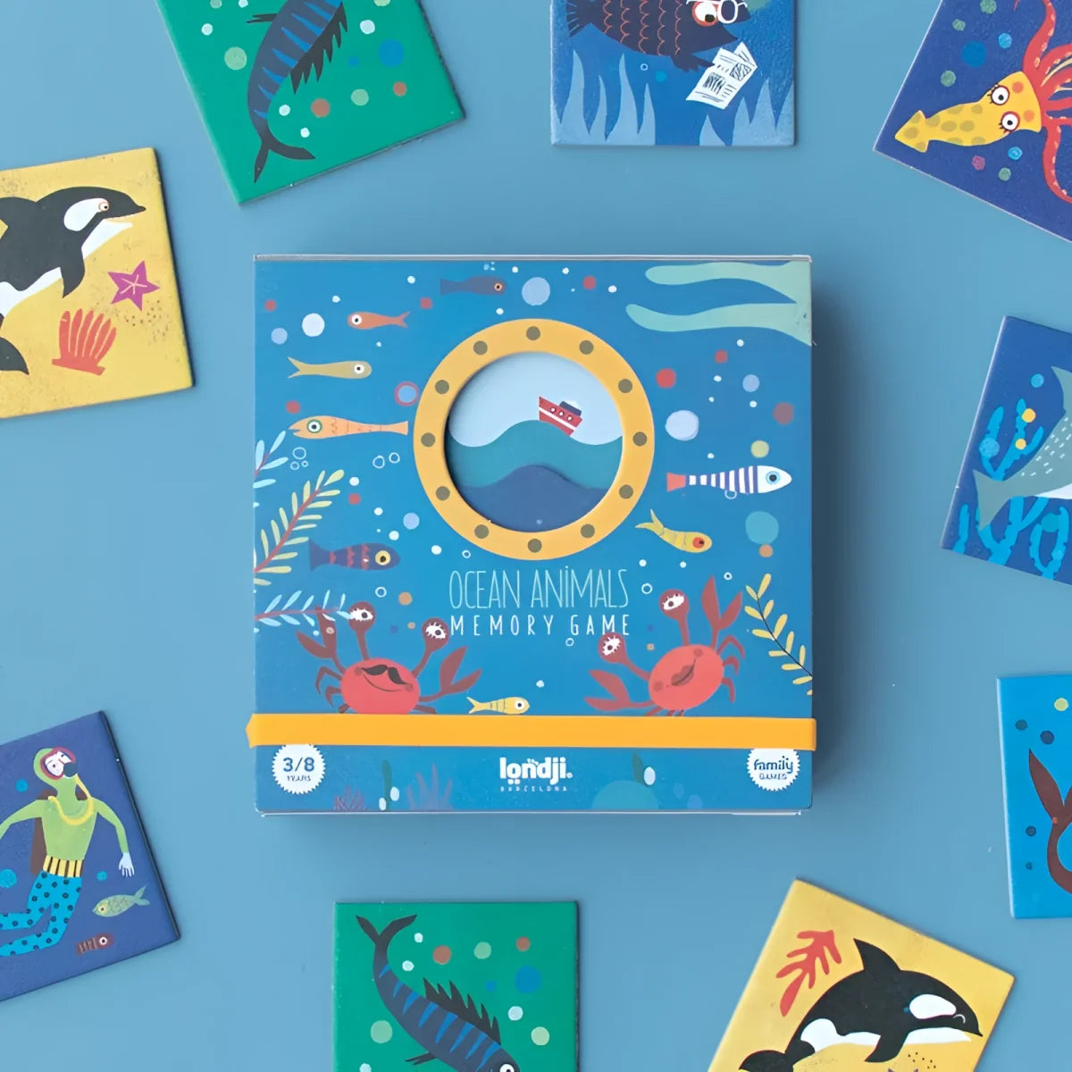 Blaue Kartonbox mit gelbem Bullauge, bunten Ozeantieren und Aufschrift Ocean Animals Memory Game von Londji