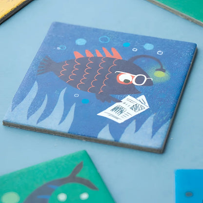 Blaues Quadrat-Coaster mit Cartoon-Fisch, orange Flossen, Brille und Zeitung aus Ocean Animals Memory
