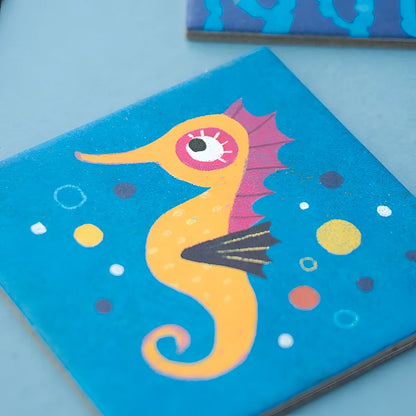 Lebhaftes gelbes Seepferdchen mit rosa Auge und lila Flossen auf blauem Untersetzer aus Ocean Animals Memory