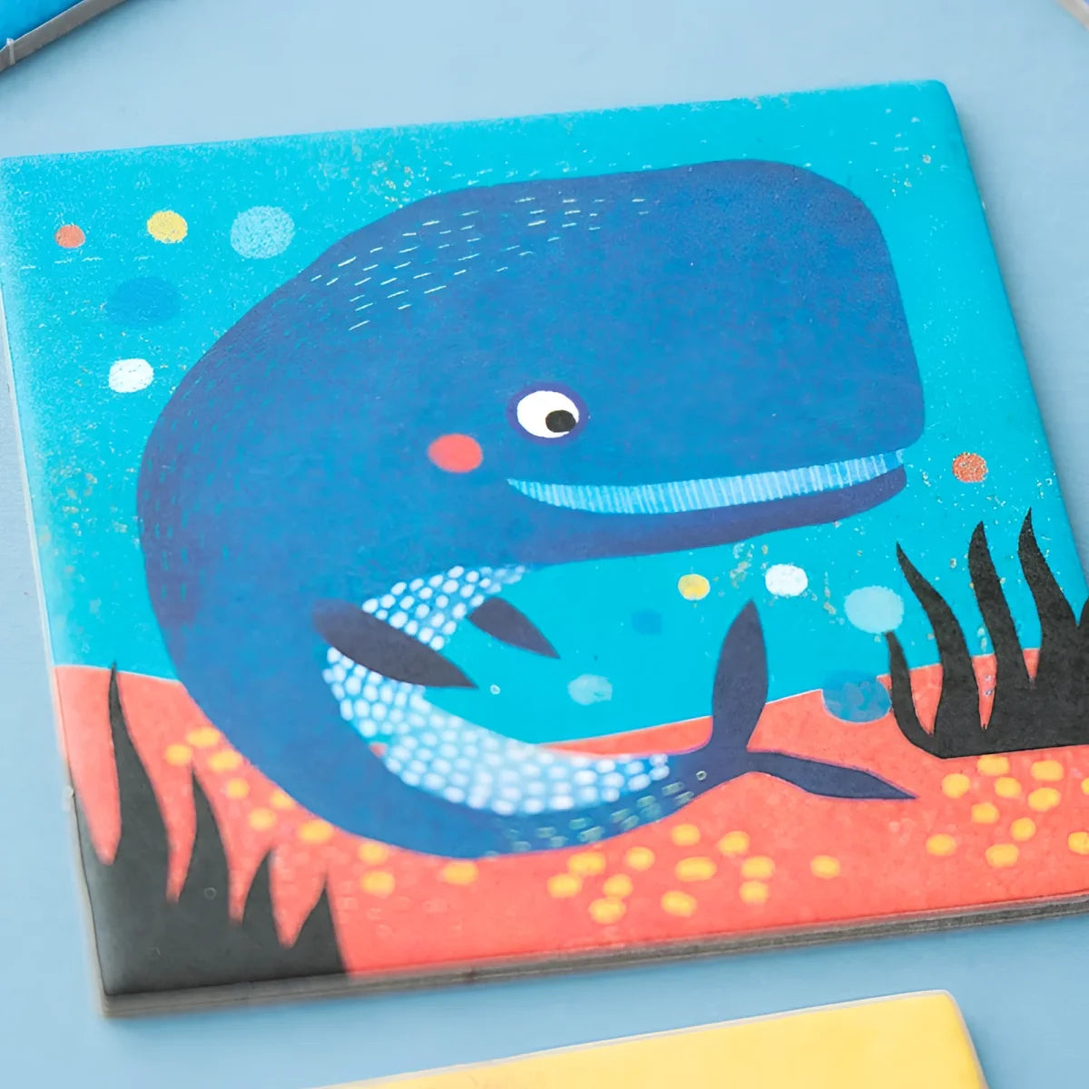 Charmes blaue Wal-Illustration auf quadratischer, texturierter Untersetzer aus Ocean Animals Memory mit Blasen und Seegras
