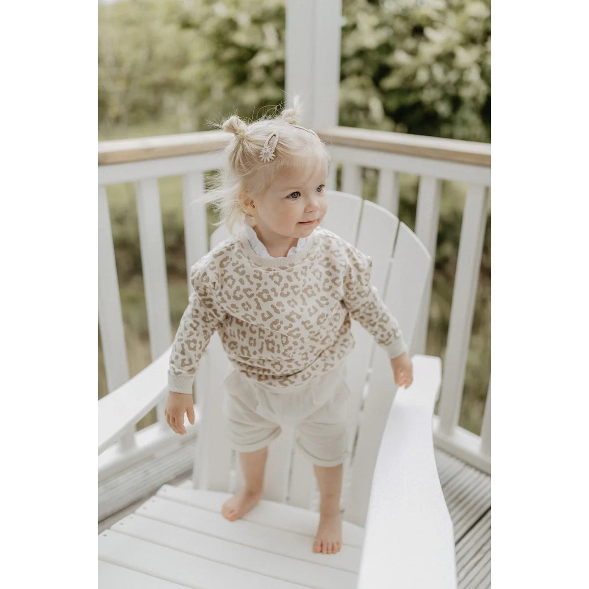 Ein kind trägt einen oversize sweater leo mit beige leopardenmuster aus nachhaltige babykleidung schweiz