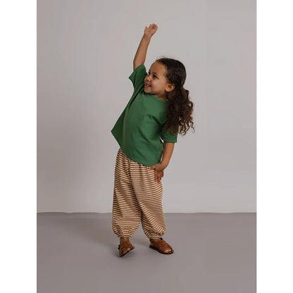 Ein kind trägt eine hose copper stripes mit kupferfarbenen streifen in beige und braun aus bequemem stoff