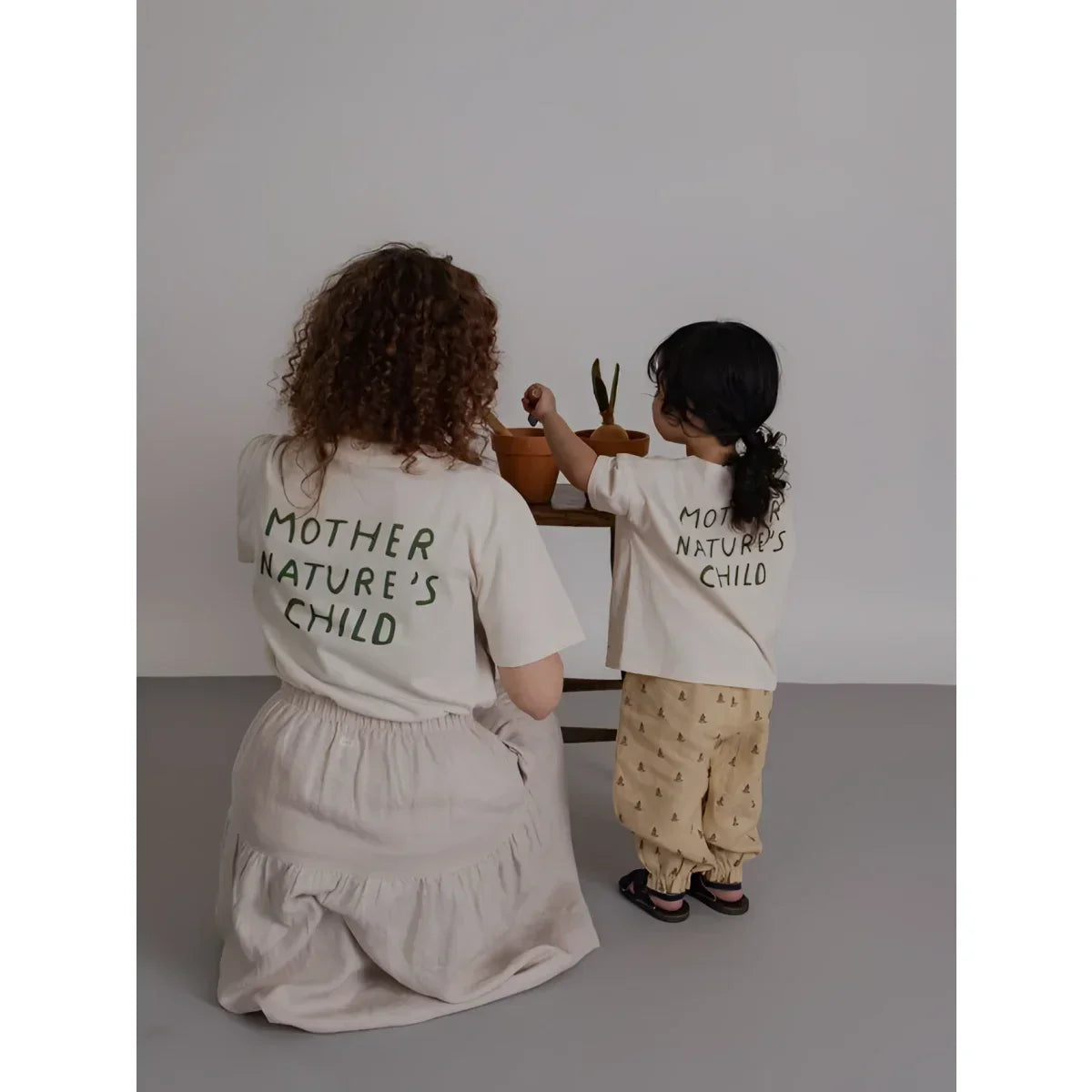 Rückenansicht: Mutter und Kind in passenden Offwhite-Shirts mit Mother Nature’s Child, Hose Lavender Bloom Gardener