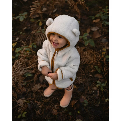 Gemütlicher weißer Teddy-Pullover mit passender Mütze und Stiefeln in Sandkaramell