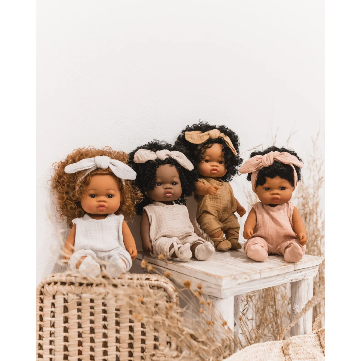 Vier diverse Baby-Puppen mit verschiedenen Hauttönen und Haartexturen in einer Reihe