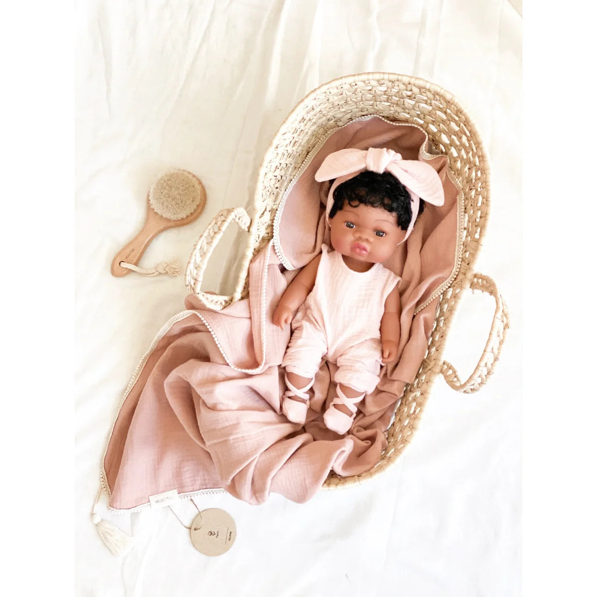 Babypuppe Loreta mit dunklen Haaren in pinker Kleidung in einem Korbträger