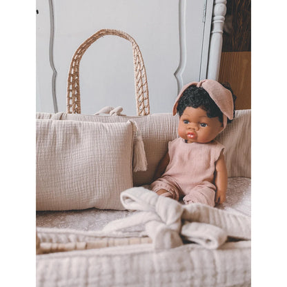 Baby-Puppe Loreta in pink Kleidung und Haarband neben einem geflochtenen Korb
