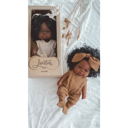 Zwei dunkelhäutige Babypuppen, eine in der Verpackung und eine auf Stoff liegend