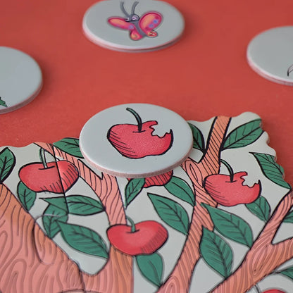 Weiße runde Knöpfe mit Apfel- und Schmetterlingsdesigns auf gemustertem Papier