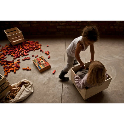 Holzspielzeug rainbow blocks in sack mit 100 bunten klötzen und kindern spielend als ökologische kinderprodukte