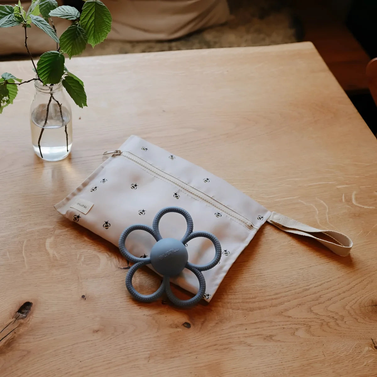 Ein weicher offwhite stoffbeutel mit schwarzem bienenmuster und grauem silicon-blumenbeißring rassel daisy