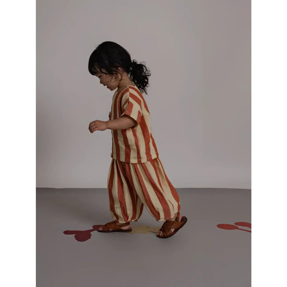 Kind auf Rückseite von Resort Pants Tomato Stripes in Rost-Creme Streifen