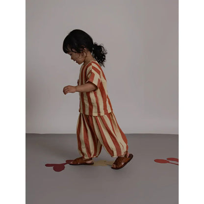 Kind auf Rückseite von Resort Pants Tomato Stripes in Rost-Creme Streifen