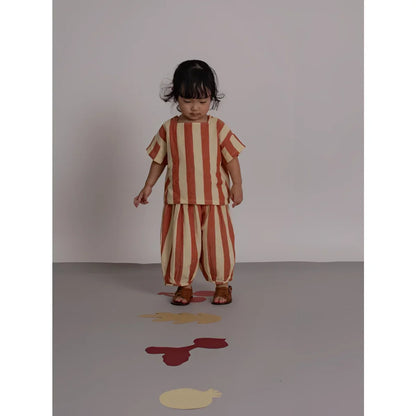 Kind auf Rückseite von Resort Pants Tomato Stripes in orange-cremefarbenen Streifen