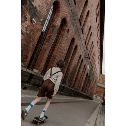Junge skateboardet in Vintage-Outfit mit Retro V-Trägern in Schokoladenbraun