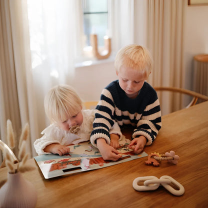 Zwei junge Kinder spielen mit einem Buch und Spielzeug aus dem Reusable Sticker Set Dino