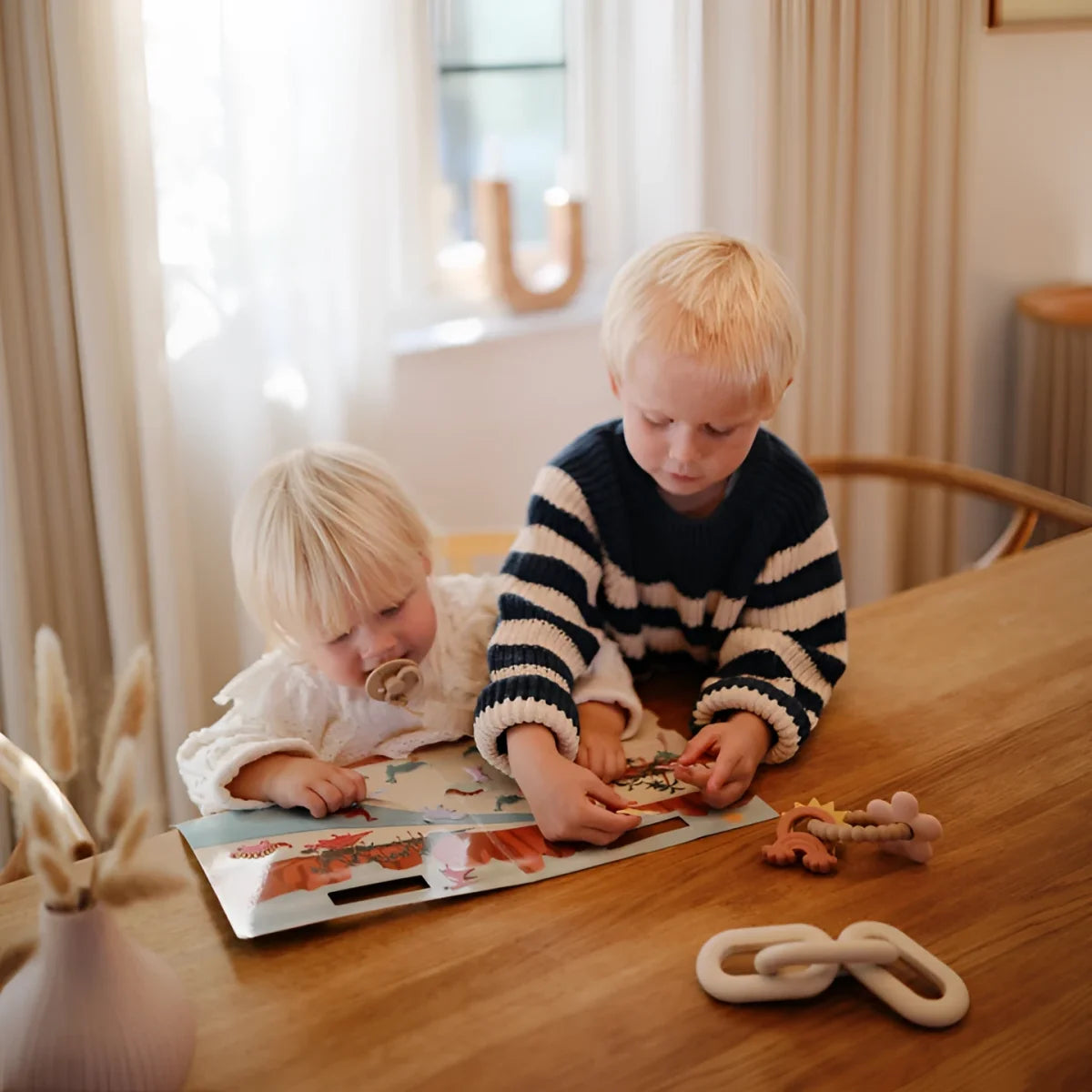 Zwei junge Kinder spielen mit einem Buch und Spielzeug aus dem Wiederverwendbaren Aufkleberset Weltraum