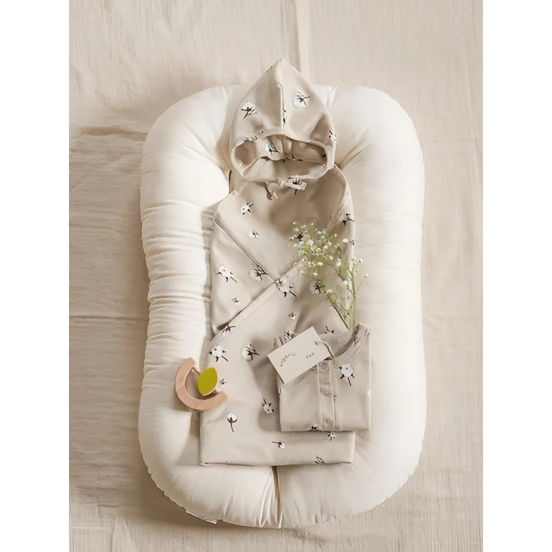 Beige Baumwoll Onesie mit weißem Löwenzahn-Print, gefaltet in Baby-Nest