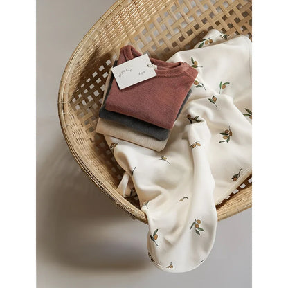 Weiche Stapel gefalteter Bio-Baumwoll-T-Shirts in Terrakotta, Beige mit Olivenblattmuster für Reversible Blanket Olive Garden
