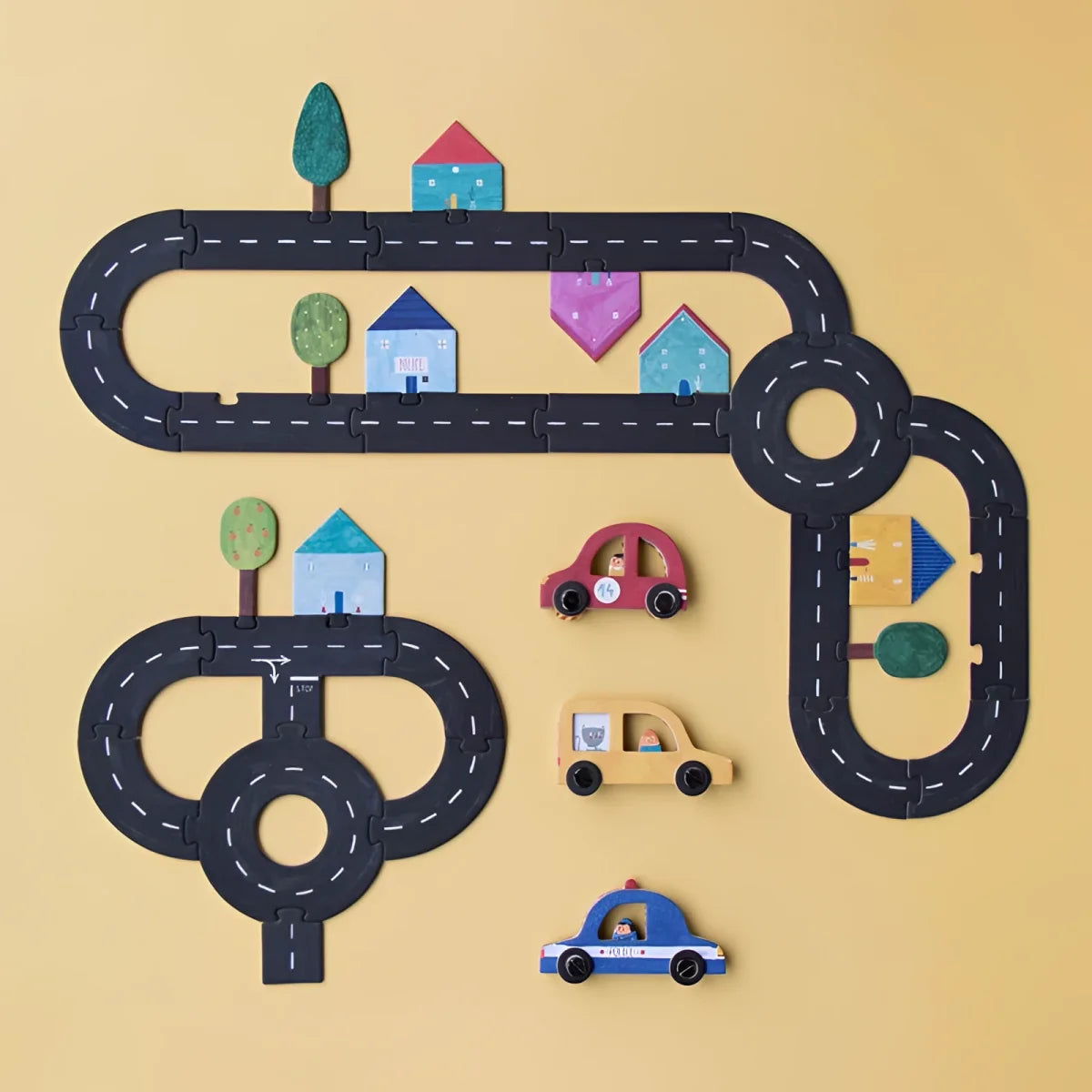 Stylisierte Straßenanordnung mit Miniaturhäusern, Bäumen und Spielzeugautos im Roads Game