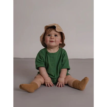 Baby in grüner kurzärmeliger seagrass beach romper aus leichtem stoff mit knopfdetails und gestreiftem strohhut